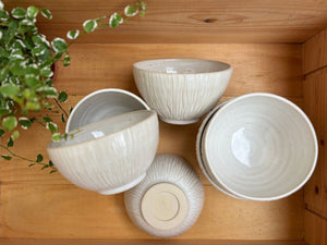 Vue de dessus de plusieurs Bols Póa avec motifs herbe, disposés dans une caisse en bois, mettant en valeur leur design artisanal.