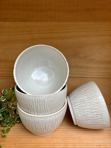 Ensemble de Bols Póa empilés, avec motifs herbe texturés, exposés sur une étagère en bois, parfaits pour un style organique.