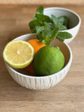 Bol Póa artisanal contenant un citron, une orange, un citron vert et des feuilles de menthe, idéal pour une table fraîche et naturelle.