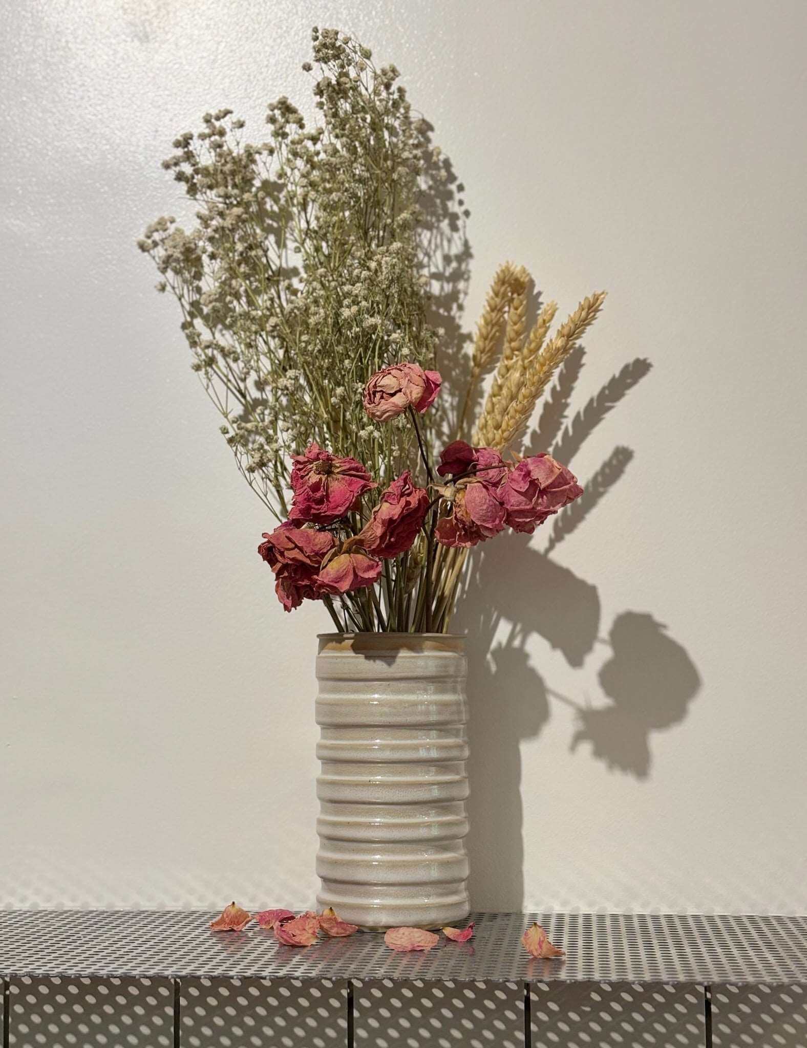 Vase Dolda en grès artisanal blanc avec lignes ondulées, contenant un bouquet de fleurs séchées, idéal pour la décoration intérieure.