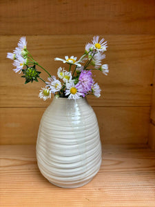 Vase Pado en céramique beige avec des fleurs sauvages colorées, placé sur une étagère en bois. Élégance artisanale pour votre maison.