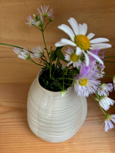 Vue rapprochée du Vase Pado beige avec des fleurs sauvages, mettant en valeur ses détails ondulés et son design fait main.