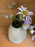 Vue rapprochée du Vase Pado beige avec des fleurs sauvages, mettant en valeur ses détails ondulés et son design fait main.